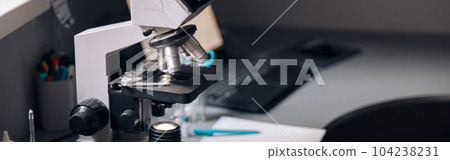 Microscope, rack with test tubes and vials on table in laboratory 104238231