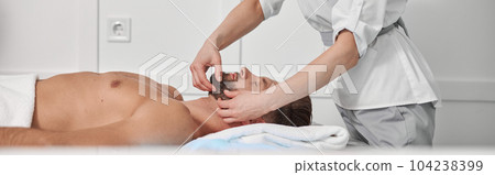 Massage therapist works with chin of bearded client in clinic office 104238399