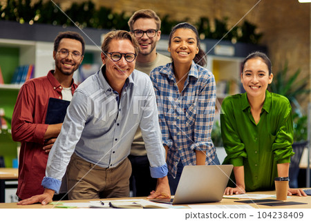 Group of young successful multi ethnic business team looking at camera and smiling while having a meeting in the modern office and coworking space Group of young successful multi ethnic business team looking at camera and smiling while having a meeting in the modern office and coworking space 104238409
