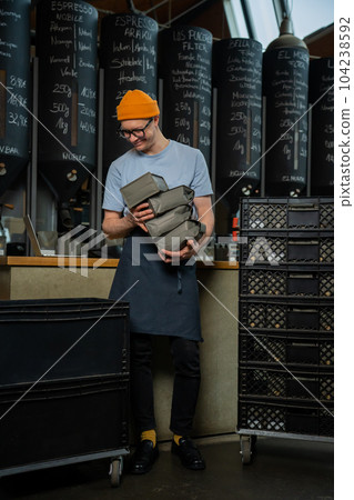 Barista bartender unloads new batch of coffee for coffee brewing in cafe. Barista bartender unloads new batch of coffee for coffee brewing in cafe. 104238592