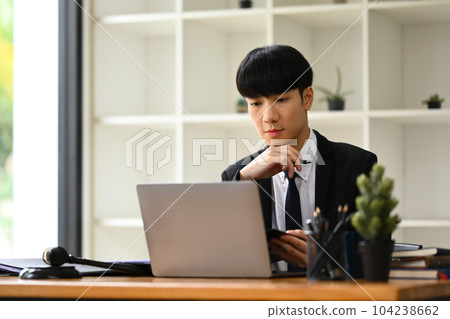 Millennial asian man manager looking at laptop screen, working on marketing project at her office Millennial asian man manager looking at laptop screen, working on marketing project at her office 104238662