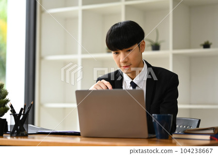 Portrait of millennial male executive in formalwear looking at laptop screen checking marketing research or statistics data Portrait of millennial male executive in formalwear looking at laptop screen checking marketing research or statistics data 104238667