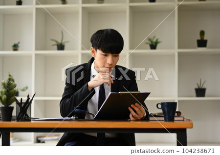 Focused young businessman analyzing financial data and planning marketing strategy at workplace Focused young businessman analyzing financial data and planning marketing strategy at workplace 104238671