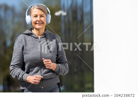 Woman in sportswear and headphones having morning run in the park Woman in sportswear and headphones having morning run in the park 104238672