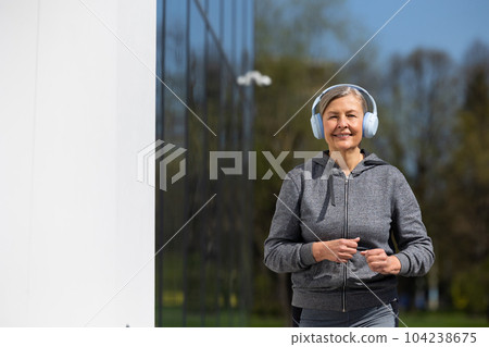 Woman in sportswear and headphones having morning run in the park 104238675