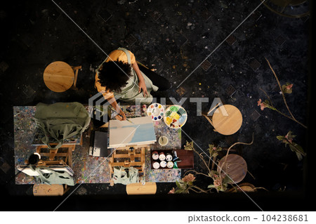From above view of skilled female student painting picture on canvas in dark creative studio. Art, education and creative hobby concept From above view of skilled female student painting picture on canvas in dark creative studio. Art, education and creative hobby concept 104238681