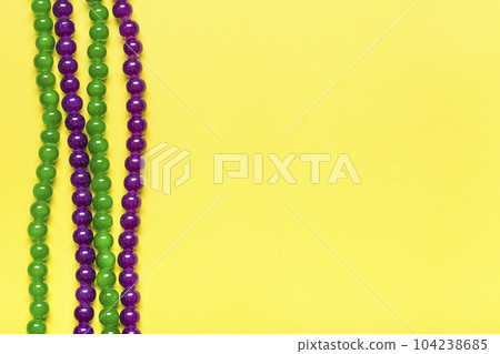 purple and green beads on yellow background Top view 2022 Mardi Gras Parade Schedule Mockup Copy space. purple and green beads on yellow background Top view 2022 Mardi Gras Parade Schedule Mockup Copy space. 104238685