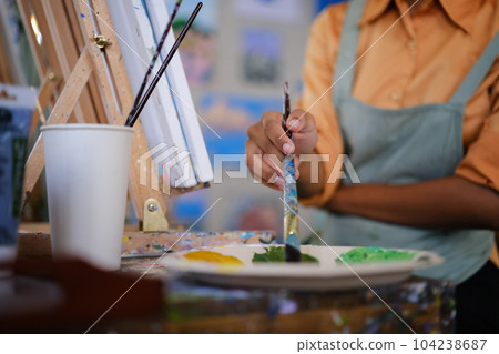 Closeup view of female artist mixing color oil painting on palette. Art, hobby and leisure activity concept Closeup view of female artist mixing color oil painting on palette. Art, hobby and leisure activity concept 104238687