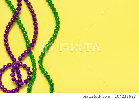 purple and green beads on yellow background Top view 2022 Mardi Gras Parade Schedule Mockup Copy space. purple and green beads on yellow background Top view 2022 Mardi Gras Parade Schedule Mockup Copy space. 104238688