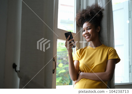 Charming African American woman checking social media, chatting on smartphone. Concept of technology, communication and lifestyle Charming African American woman checking social media, chatting on smartphone. Concept of technology, communication and lifestyle 104238713