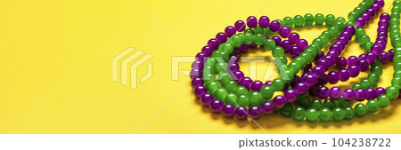 purple and green beads on yellow background Top view 2022 Mardi Gras Parade Schedule Mockup Copy space. purple and green beads on yellow background Top view 2022 Mardi Gras Parade Schedule Mockup Copy space. 104238722