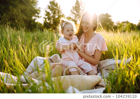 Mother and daughter playing together in summer park at sunset. Happy mom with small child having fun 104239110