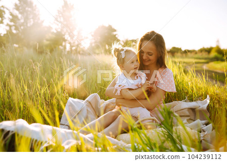 Mother and daughter playing together in summer park at sunset. Happy mom with small child having fun 104239112