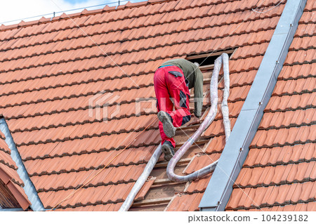 craftsman on the stairs, blowing foam roof insulation, application with the help of a pressure hose 104239182