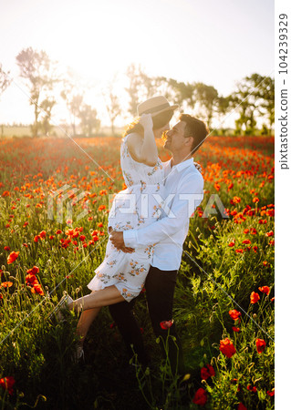 Loving couple in the poppy field at sunset. Enjoying time together. love and lifestyle. 104239329