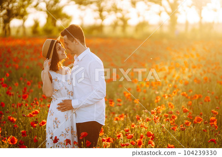 Loving couple in the poppy field at sunset. Enjoying time together. love and lifestyle. 104239330