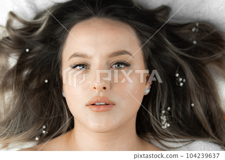 Attractive look beautiful woman who lies relaxed. Conveys magical beauty woman's face where purity and rejuvenation skin are replaced by natural shine and embodiment unique attractiveness and beauty. Attractive look beautiful woman who lies relaxed. Conveys magical beauty woman's face where purity and rejuvenation skin are replaced by natural shine and embodiment unique attractiveness and beauty. 104239637