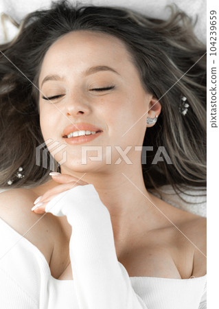 A beautiful and charming woman smiles, lying contented and with her eyes closed. Enjoys himself and rests after cosmetic care. Confident and in harmony with herself and the world A beautiful and charming woman smiles, lying contented and with her eyes closed. Enjoys himself and rests after cosmetic care. Confident and in harmony with herself and the world 104239659