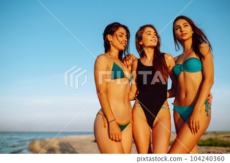 Portrait of three beautiful girls on the beach. Young women enjoying on beach holiday. Summer holidays. 104240360