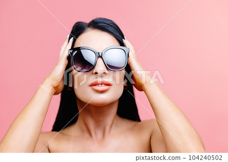 Sexy woman in black swimsuit with sunglasses isolated on pink background in studio. Sexy woman in black swimsuit with sunglasses isolated on pink background in studio. 104240502