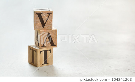 Pile with three wooden cubes - letters VAT meaning Value Added Tax on them, space for more text / images at right side. 104241208