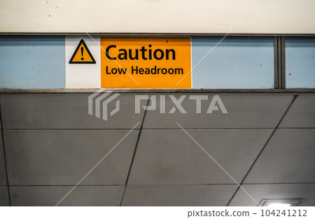 Orange " Caution low headroom " sign on roof above elevators 104241212