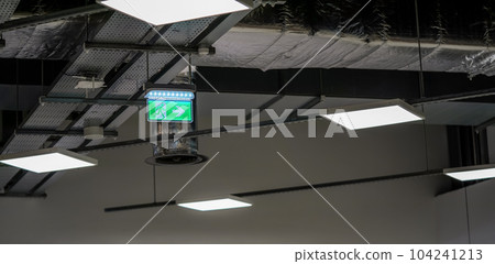 Illuminated green emergency / fire exit sign with running man pictogram on industrial roof. Illuminated green emergency / fire exit sign with running man pictogram on industrial roof. 104241213