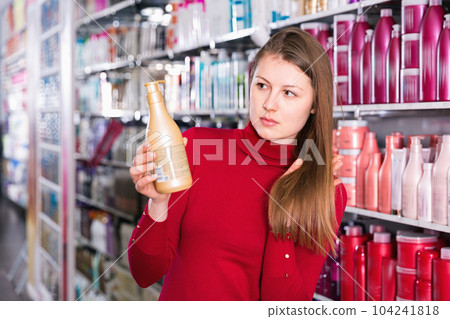Young woman is demonstraiting new conditioner in hair care store. 104241818