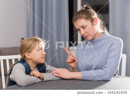 Mother threatens the finger of her little daughter 104241939