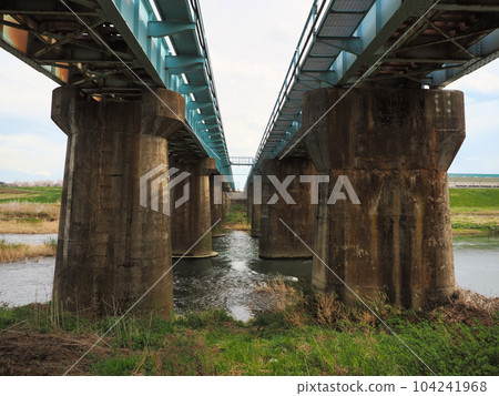 Looking up from the riverbed to the old concrete bridge piers of the tracks 104241968