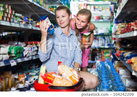 Woman and girl with shopping basket choosing rice Woman and girl with shopping basket choosing rice 104242209