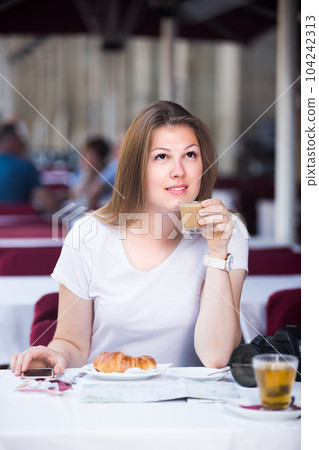 Young tourist girl is drinking coffee and chatting 104242313