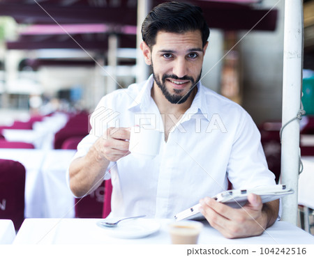 Man drinking coffee in summer cafeteria 104242516