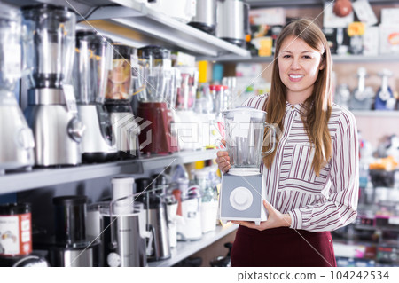 Positive saleswoman offering blender in shop 104242534