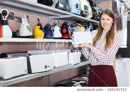 Saleswoman offering toaster in household appliances shop Saleswoman offering toaster in household appliances shop 104242552