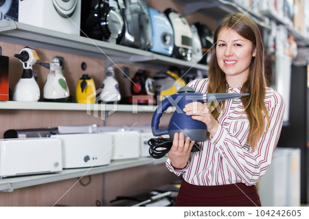 Smiling saleswoman offering steam cleaner Smiling saleswoman offering steam cleaner 104242605