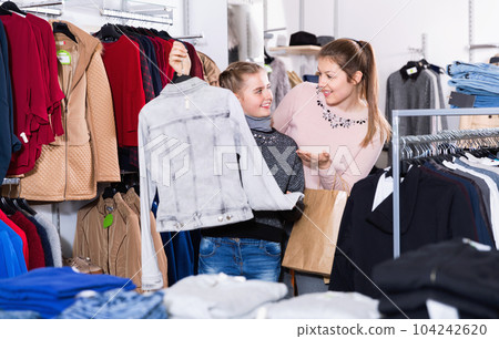 Smiling preteen girl with young mother shopping for clothes in shop Smiling preteen girl with young mother shopping for clothes in shop 104242620