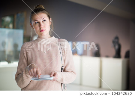 Adult female looking at exhibition in museum Adult female looking at exhibition in museum 104242680