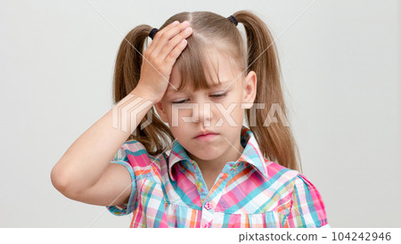 Child with headache holding hand on head on white background caucasian little girl 6-7 years looking down on gray background Child with headache holding hand on head on white background caucasian little girl 6-7 years looking down on gray background 104242946