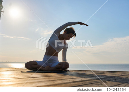 Caucasian woman practicing yoga at seashore of tropic ocean Caucasian woman practicing yoga at seashore of tropic ocean 104243264