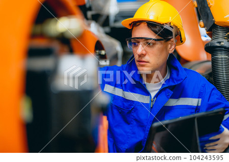 Professional maintenance worker with machine robotic arms at industrial factory 104243595