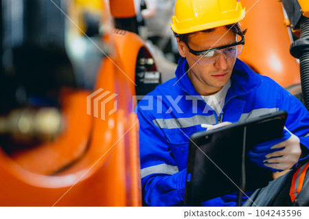 Professional maintenance worker with machine robotic arms at industrial factory 104243596