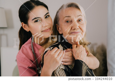 Happy caregiver and senior patient smiling and looking at camera Happy caregiver and senior patient smiling and looking at camera 104244010