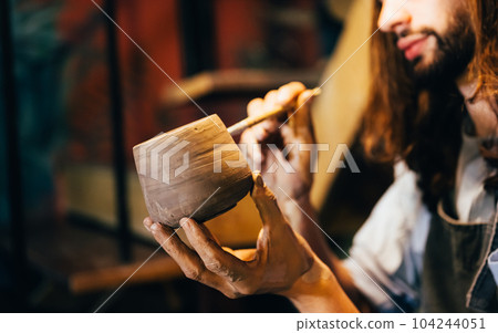 Craftsman potter making jug of clay on the potter's wheel circle in workshop Craftsman potter making jug of clay on the potter's wheel circle in workshop 104244051