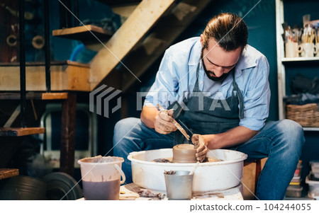 Craftsman potter making jug of clay on the potter's wheel circle in workshop Craftsman potter making jug of clay on the potter's wheel circle in workshop 104244055