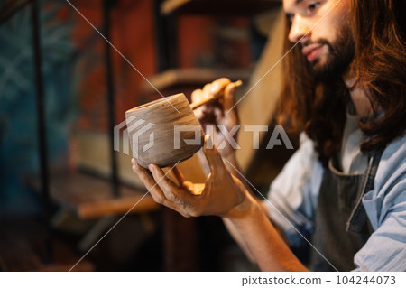 Craftsman potter making jug of clay on the potter's wheel circle in workshop Craftsman potter making jug of clay on the potter's wheel circle in workshop 104244073