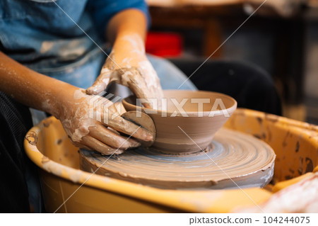 Close up on skillful hands sculpting pottery jar on potter wheel Close up on skillful hands sculpting pottery jar on potter wheel 104244075
