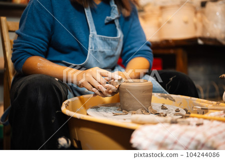 Close up on skillful hands sculpting pottery jar on potter wheel 104244086