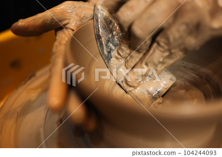 Close up on skillful hands sculpting pottery jar on potter wheel Close up on skillful hands sculpting pottery jar on potter wheel 104244093