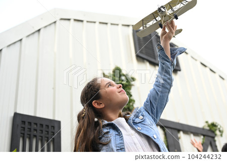 Portrait of girl holding plane toy and smiling to camera 104244232